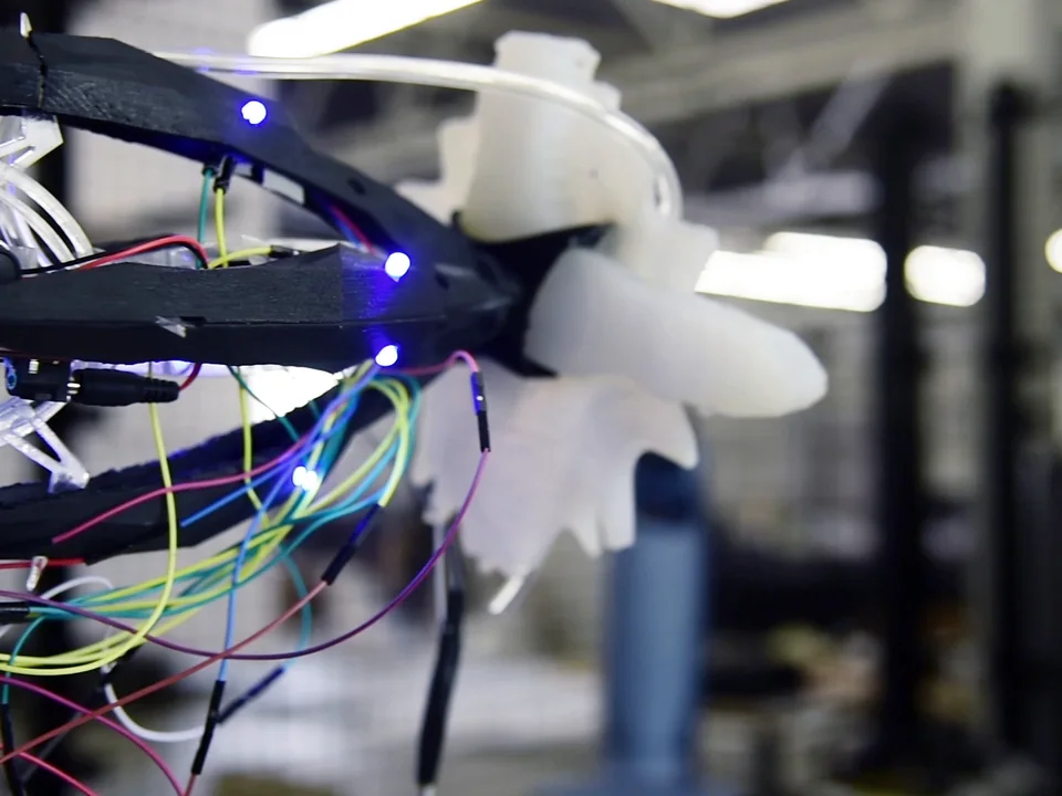 A KUKA robot arm with a 3D-printed shell, wiring, and a white silicone gripper